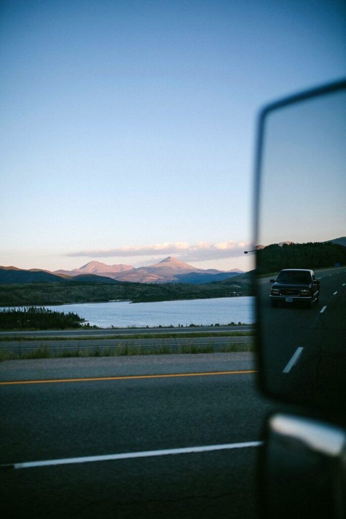 Car side mirror on a lakeside road